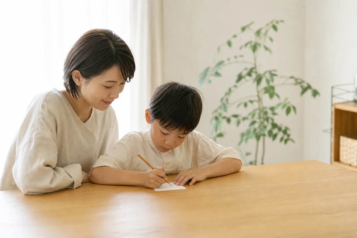 紙のカードに鉛筆で書き込む子ども